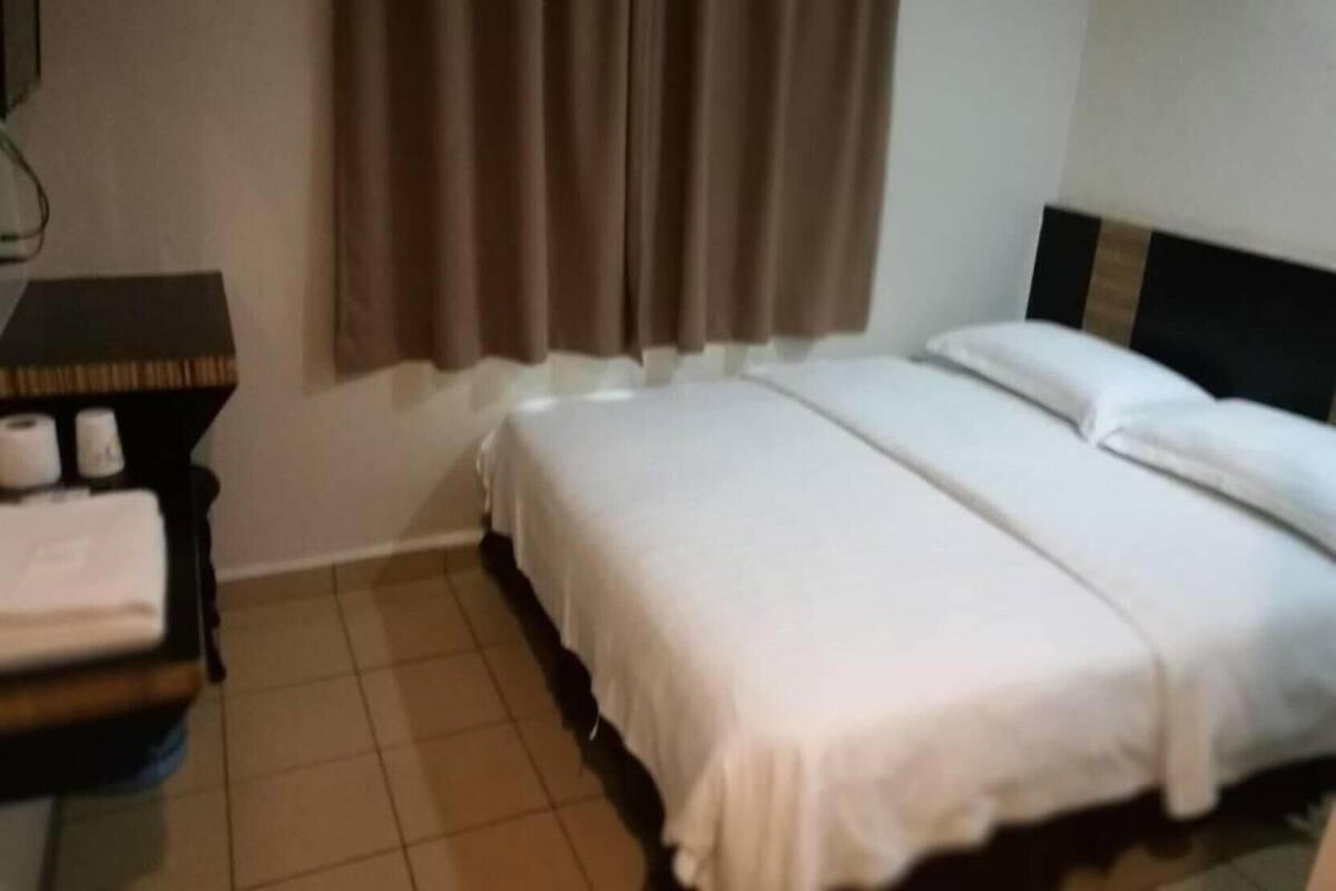 Ein Hotelzimmer mit Bett, Nachttisch und einem Fenster mit Vorhängen.