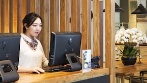 A reception desk with two computer monitors, a person at the desk, and a wooden panel wall in the background. - Hotel Clover 769 North Bridge Road (Singapore)