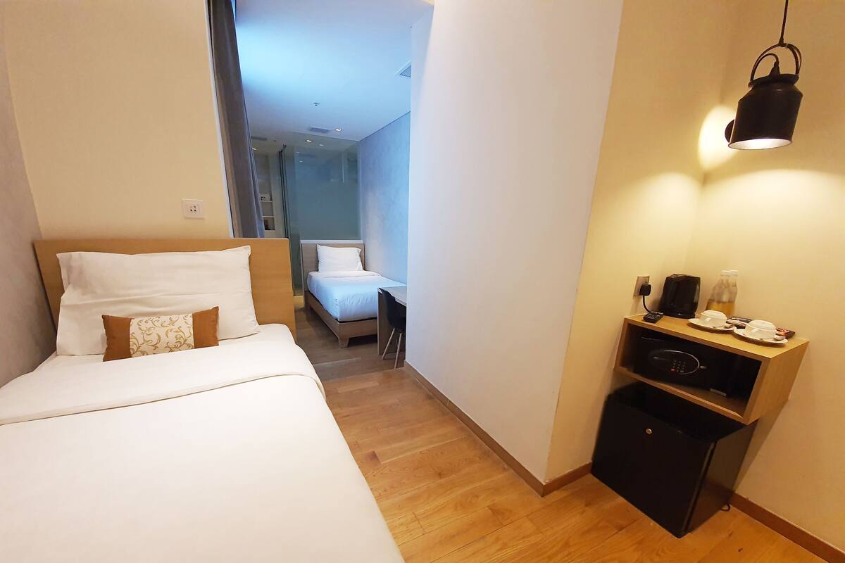 A hotel room with a bed, a desk, a coffee machine, and a bottle of water.