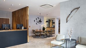A modern hotel lobby with a reception desk, seating area, and a dining space. - Hotel Clover 769 North Bridge Road (Singapore)