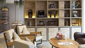 A modern living room with a wooden bookshelf, comfortable seating, and a round coffee table. - Hotel Clover 769 North Bridge Road (Singapore)