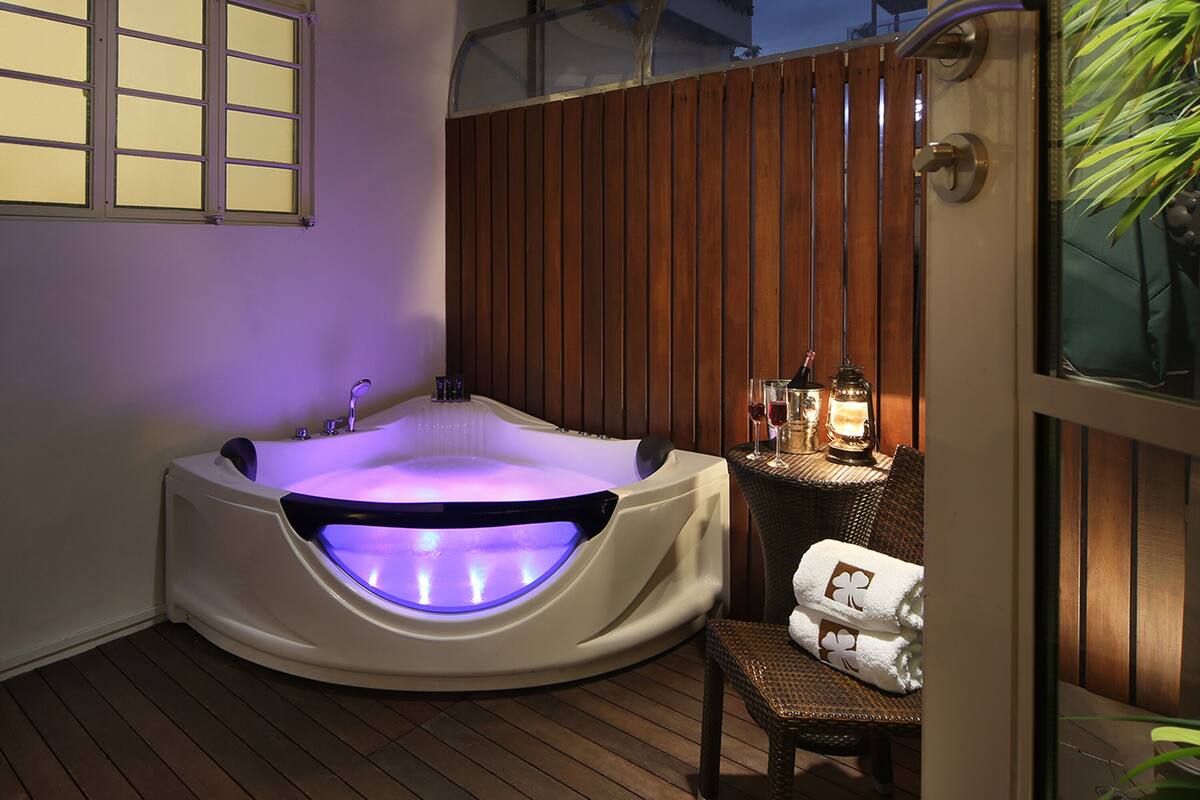 A hot tub with a built-in light, a wooden fence, and a chair with towels.