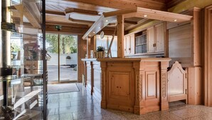 Un interior de madera con una barra central, puertas de cristal que dan al exterior y un suelo de baldosas.