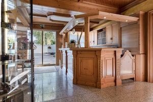 Un interior de madera con una barra central, puertas de cristal que dan al exterior y un suelo de baldosas.