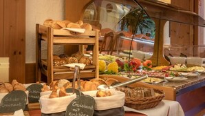 Un bufé de desayuno con panes, bollería y una selección de frutas y quesos.