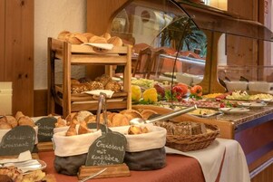 Un bufé de desayuno con panes, bollería y una selección de frutas y quesos.
