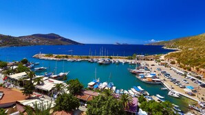 A marina with boats docked, a clear blue sky, and a hilly landscape in the background. - Zinbad Hotel (Kas)