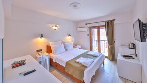 A hotel room with a large bed, bedside tables, a desk with a chair, a TV, and an air conditioning unit. - Zinbad Hotel (Kas)
