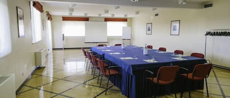 A conference room with a long table, chairs, and a projector screen.