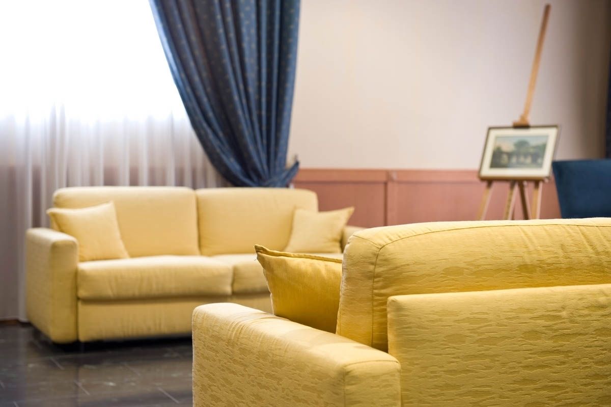 Um quarto com um sofá amarelo e um quadro na parede.