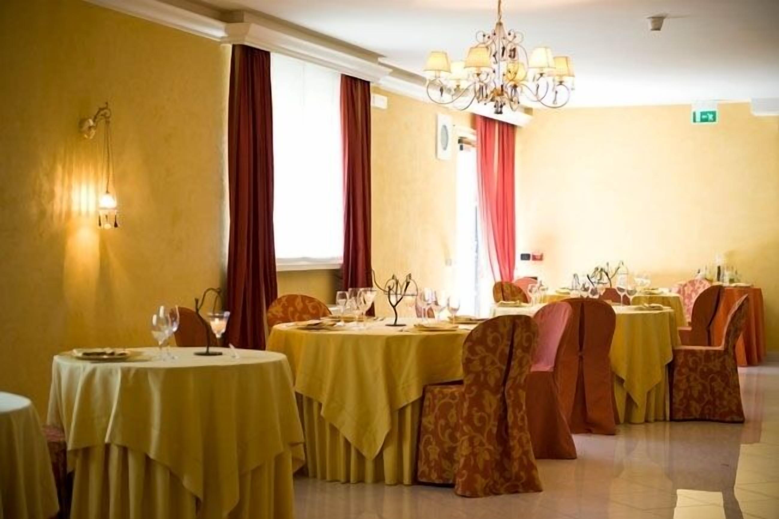 Un comedor con mesas redondas, sillas y una araña.
