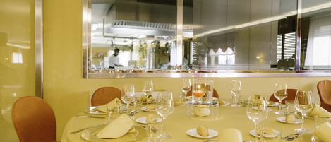 A restaurant with a yellow tablecloth, neatly set tables, and chairs.