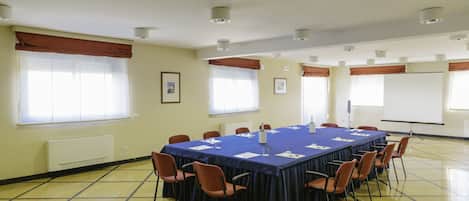 A conference room with a long table, chairs, and a projector screen.