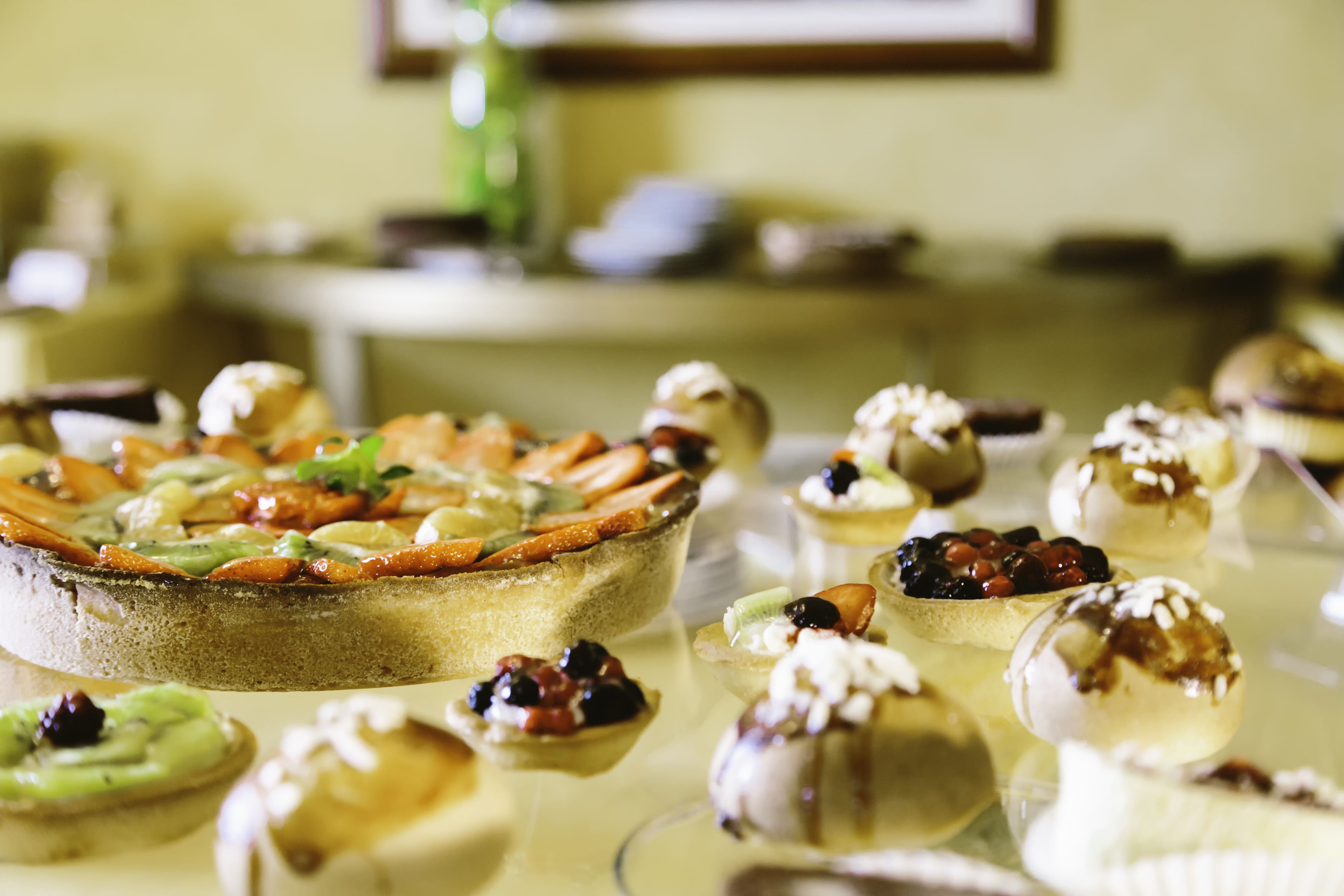 A variety of desserts on a table, including a pie and several small tarts with toppings.