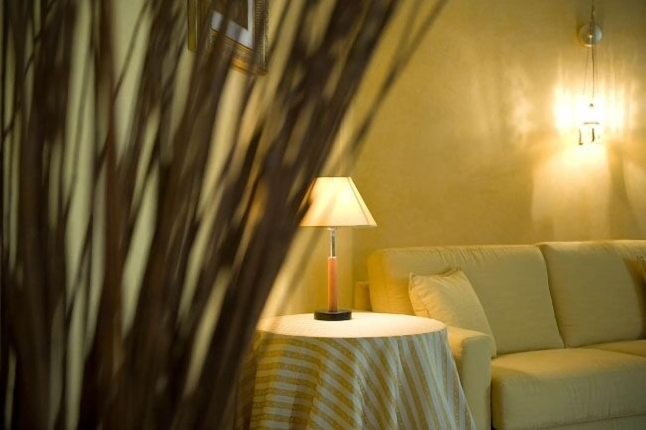 A room with a round table, a lamp, and a sofa.
