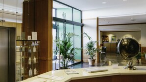A hotel reception area with a glass display case, a globe, and potted plants. - Hotel Federiciano (Valenzano)