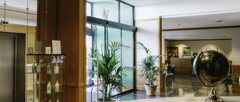A hotel reception area with a glass display case, a globe, and potted plants.