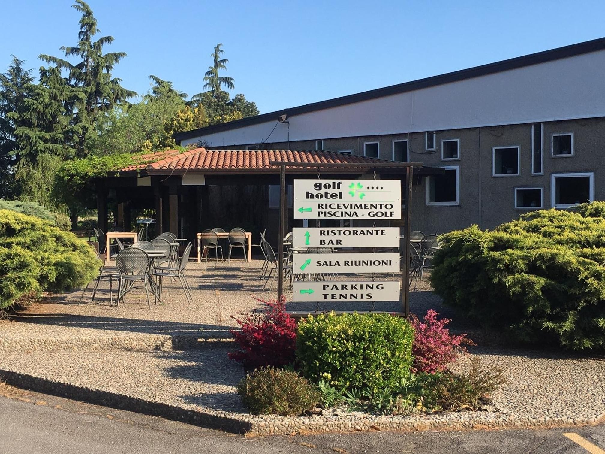 Hotel de golf con un cartel que indica servicios como restaurante, bar, cancha de tenis y estacionamiento.