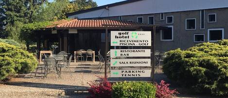 Hotel de golf con un cartel que indica servicios como restaurante, bar, cancha de tenis y estacionamiento.