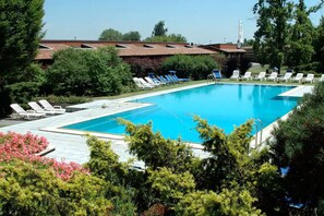 A swimming pool with lounge chairs and a hotel building in the background. - Golf Hotel (Lainate)