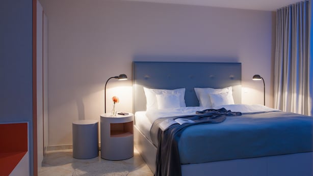 A modern bedroom with a large bed, two bedside tables, and a nightstand. - The Grey Hotel (Dortmund)