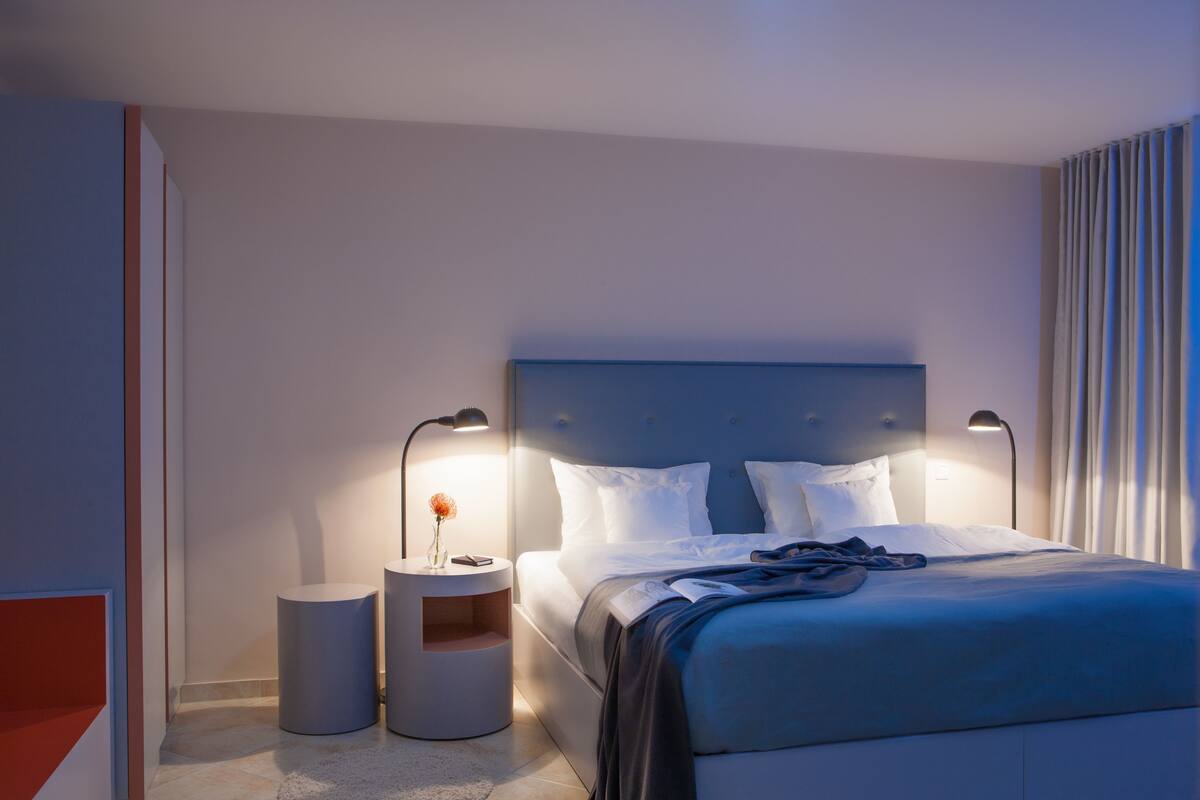 A modern bedroom with a large bed, two bedside tables, and a nightstand.