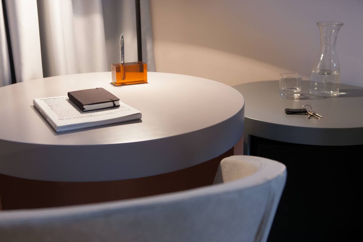 A round table with a notebook, a pen, a glass of water, and a vase.