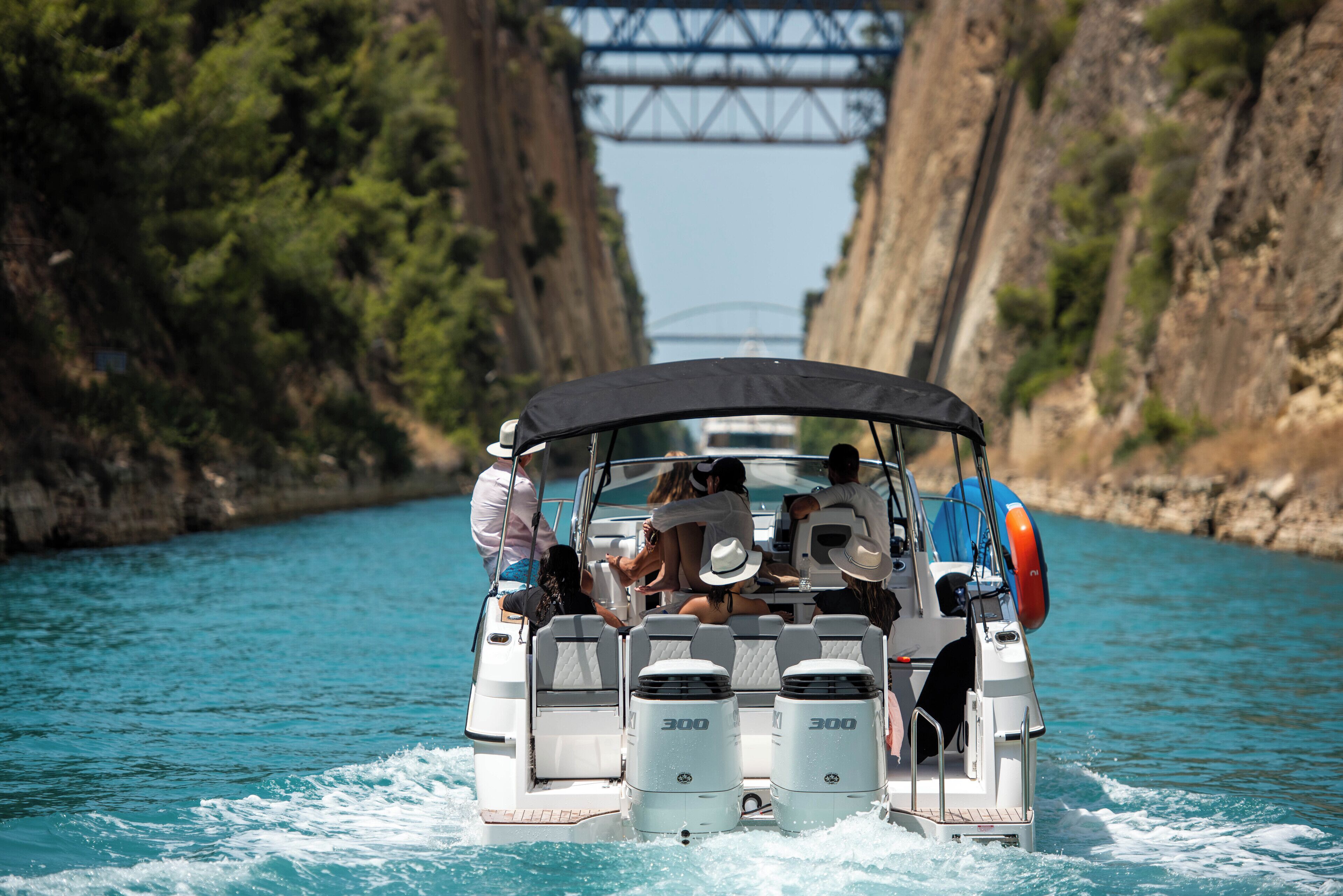Un bateau transportant des passagers, un pont en arrière-plan et un cours d’eau étroit.