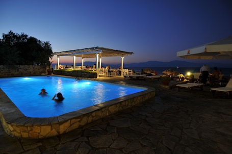 Una piscina al aire libre, sombrillas, sillones reclinables de piscina