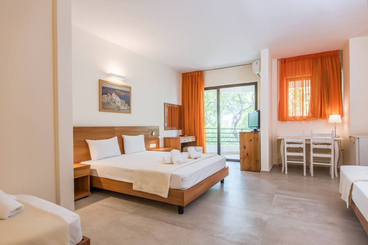 Une chambre d’hôtel avec un grand lit, un bureau avec deux chaises, une télévision et un tableau au mur.