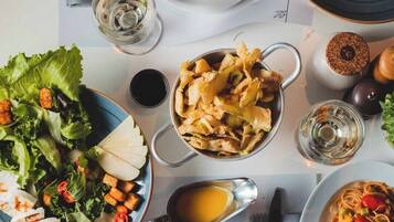 A table set with various dishes, including pasta, salad, and bread, with a menu and a glass of water.
