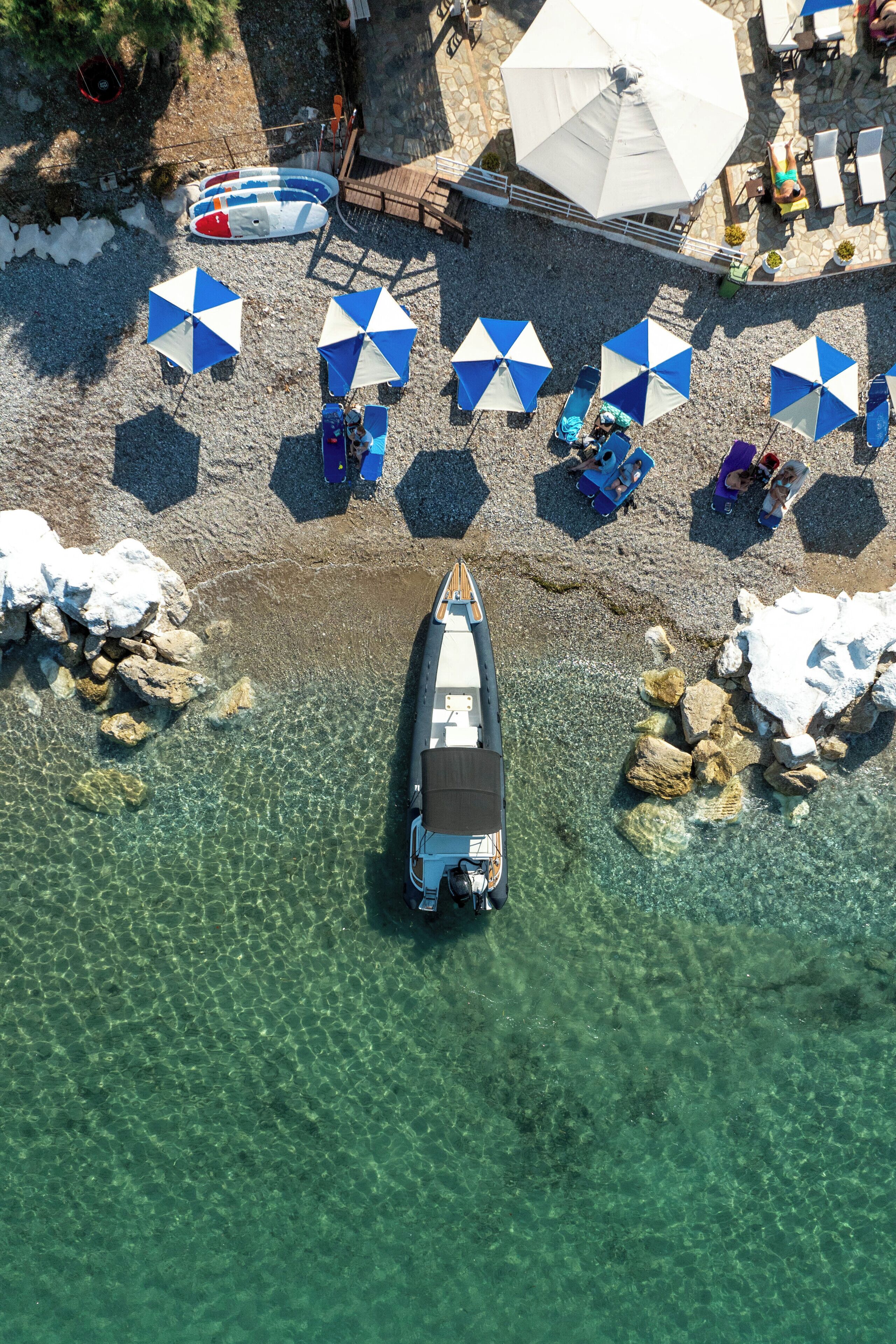 A boat docked at a beach with clear water, umbrellas, and lounge chairs.