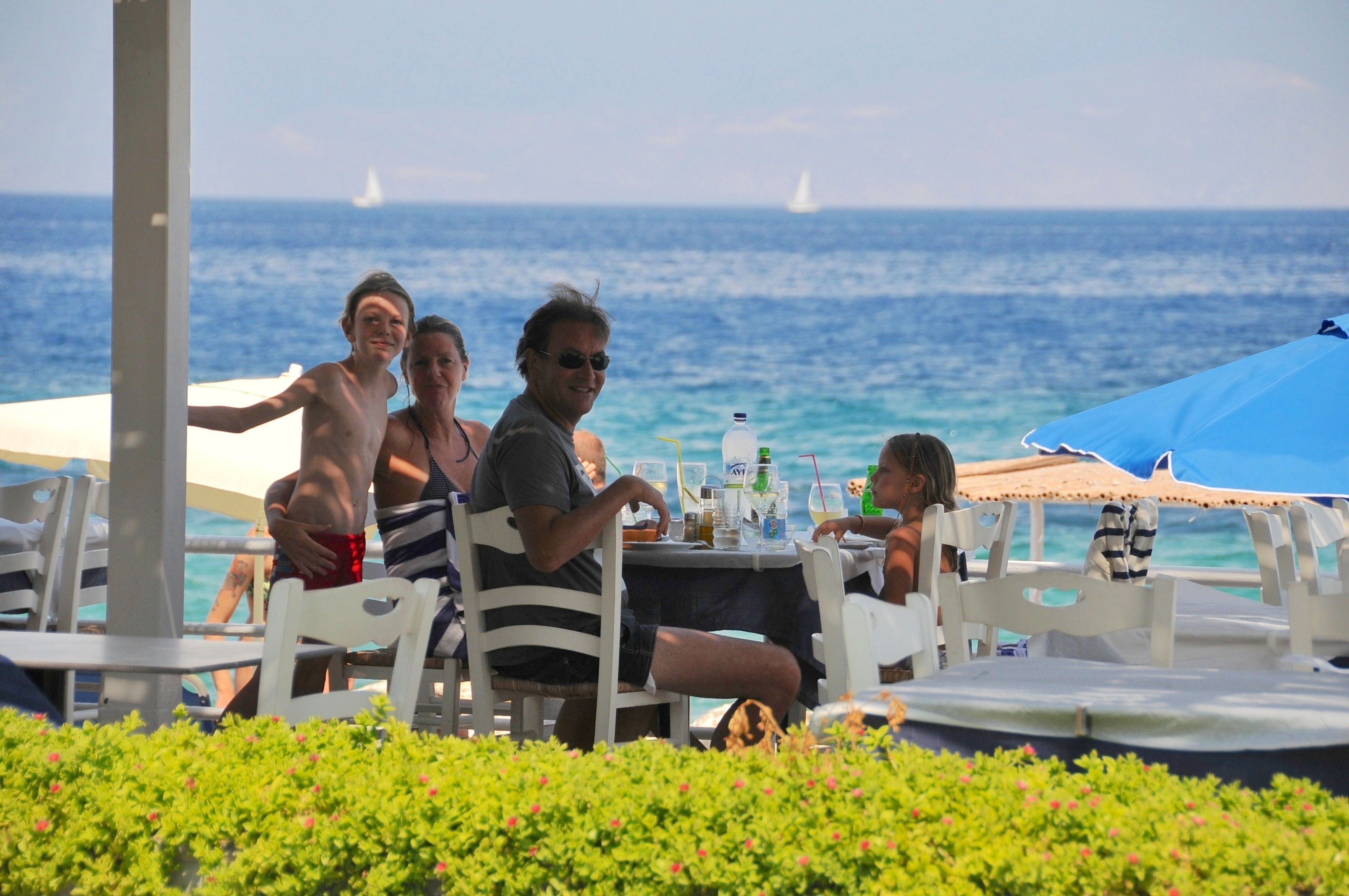 A group of people dining at an outdoor table with a view of the sea.