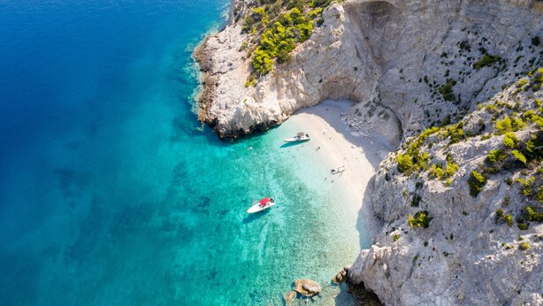 Um penhasco costeiro com uma praia e águas turquesa límpidas.