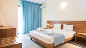 Quarto de hotel com cama de madeira, escrivaninha, mesa de cabeceira e janela com cortinas azuis.