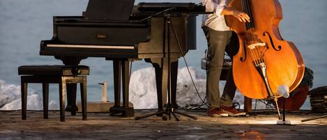 A person playing a cello next to a grand piano by a pool.