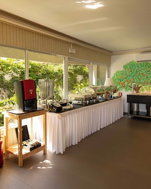 Disposició de buffet amb una màquina de cafè, una làmpada i un quadre d'un arbre amb fruita.