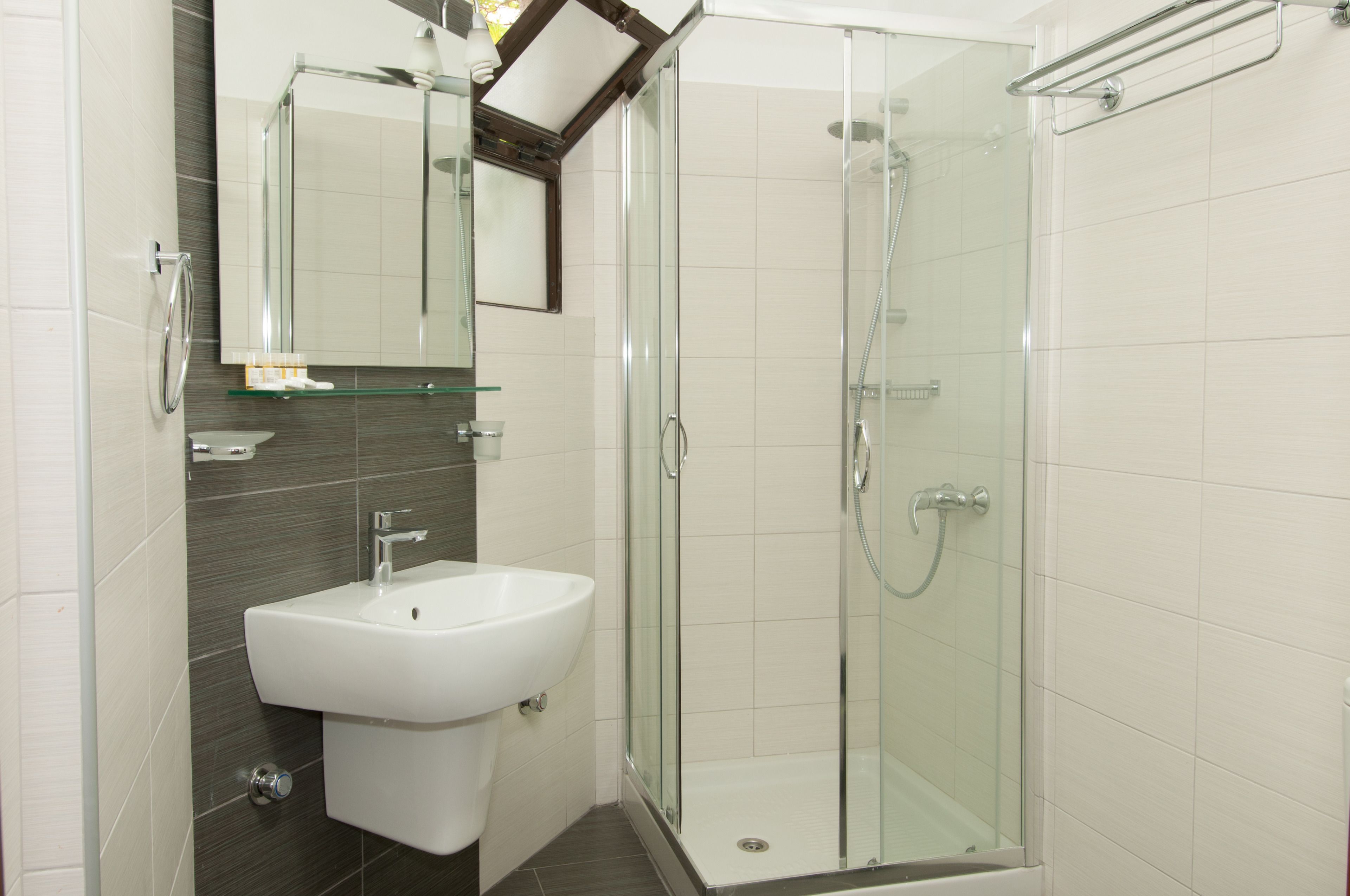 Un baño moderno con ducha envuelta en vidrio, un lavabo blanco y un espejo encima.