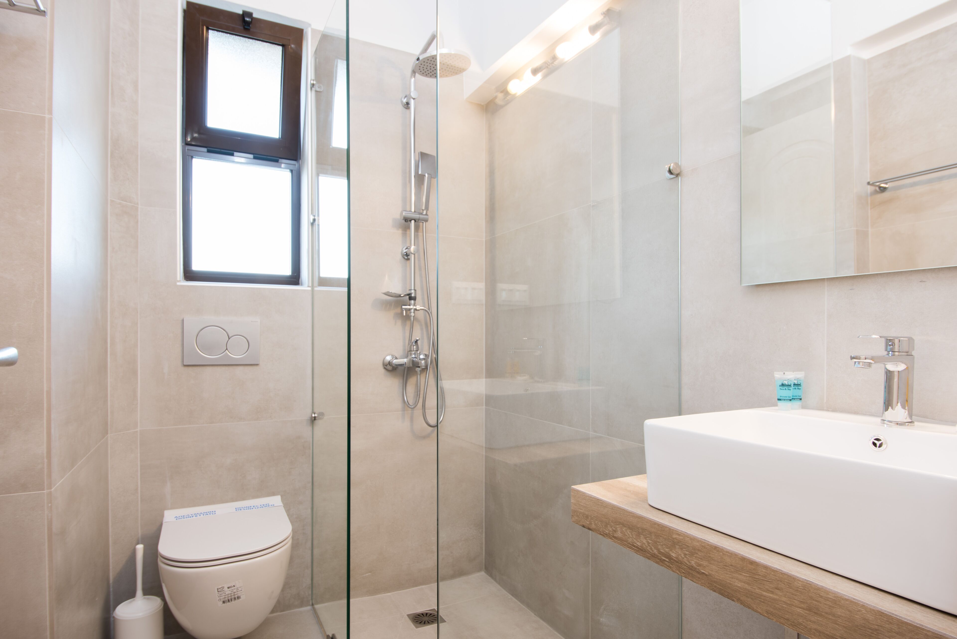 Un baño moderno con ducha de vidrio, lavamanos blanco y retrete.