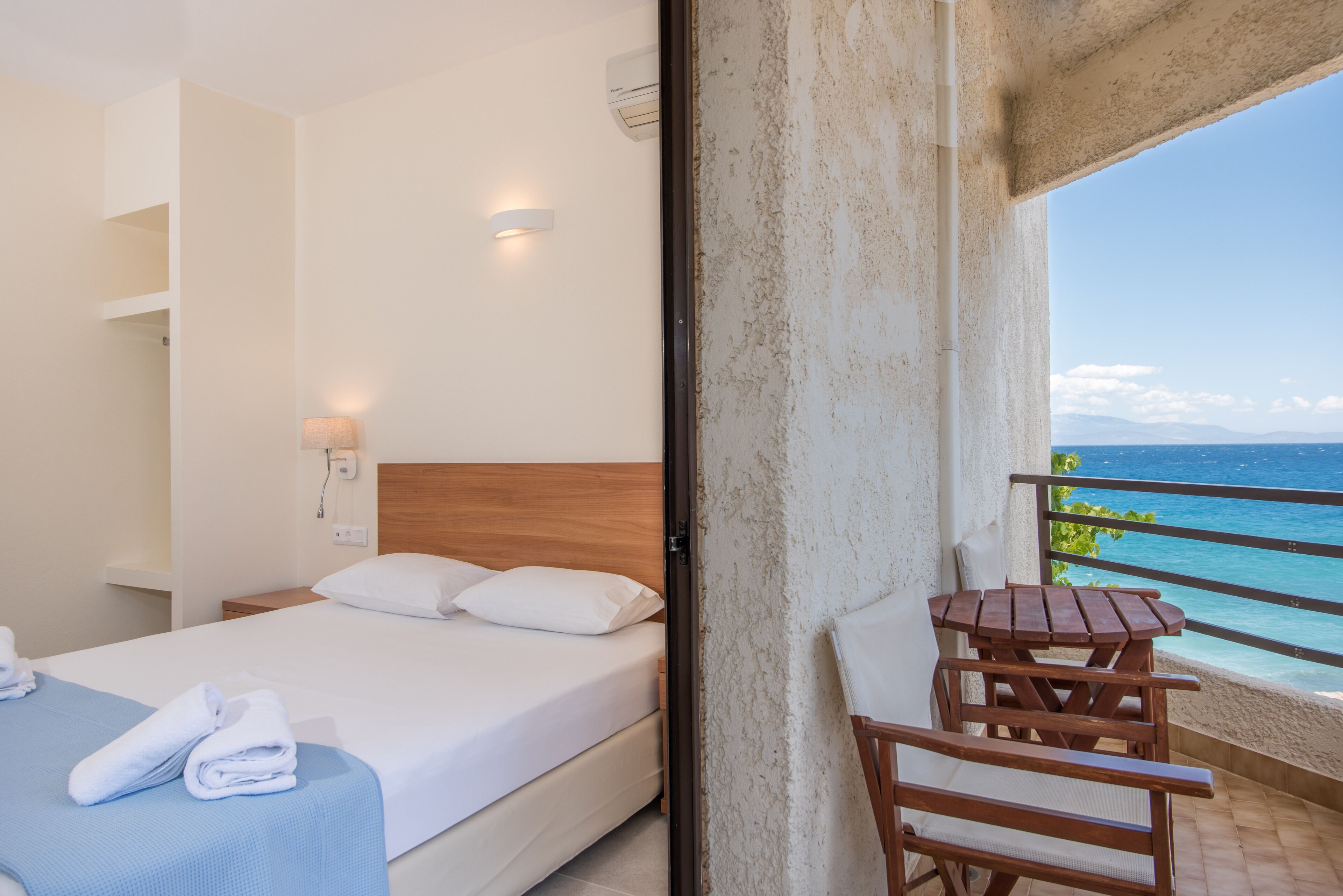 Una habitación de hotel con una cama, una mesita de noche, una mesa y vista al océano.