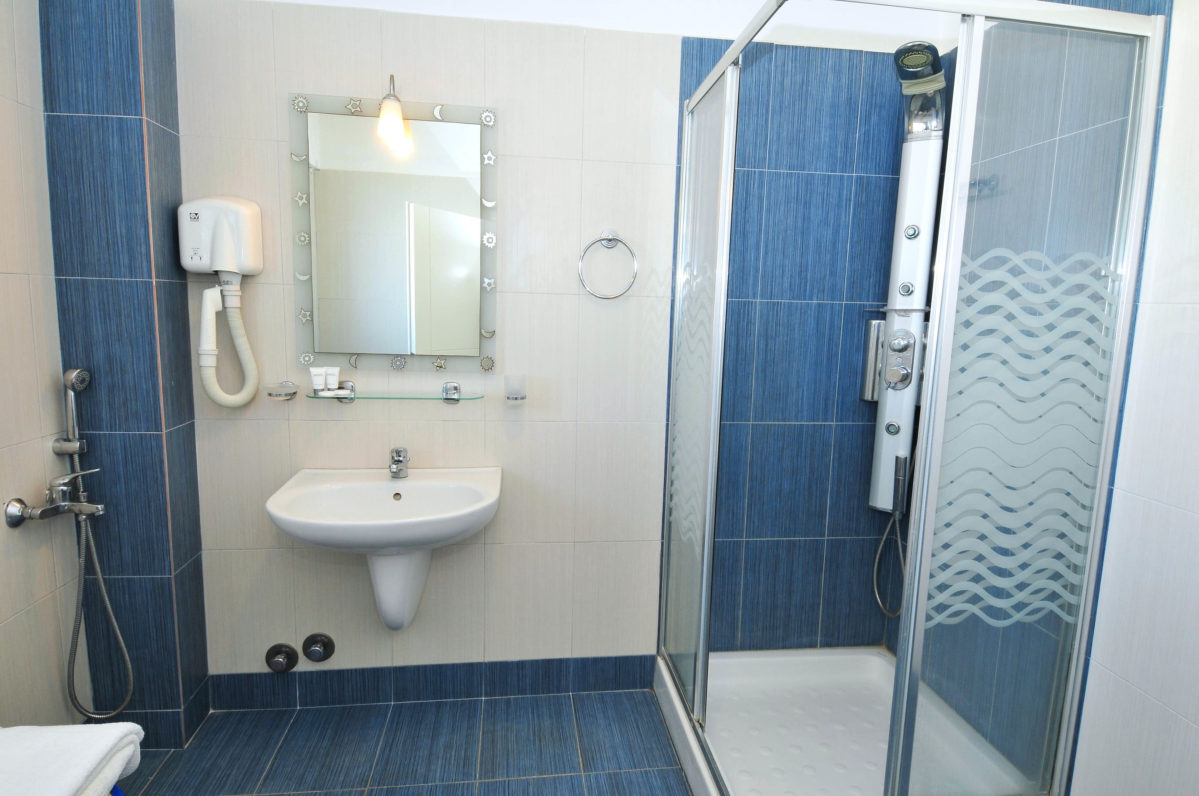 A bathroom with a sink, mirror, and shower.