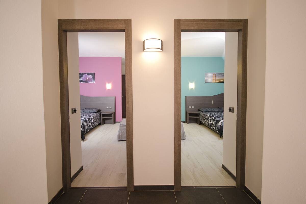 Un pasillo con dos puertas espejadas que dan a habitaciones de diferentes colores.