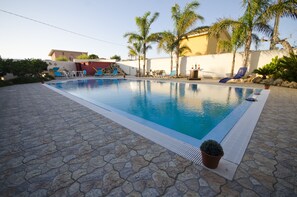 A swimming pool with lounge chairs and palm trees.