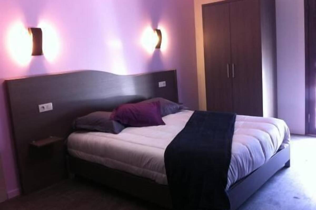 Ein Schlafzimmer mit einem Bett, Nachttischen, einem Kleiderschrank und Wandleuchten.