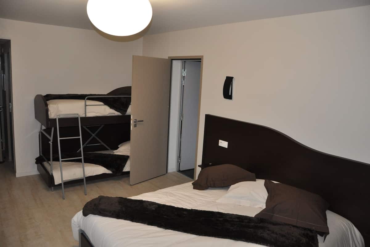 Ein Zimmer mit einem Etagenbett, einem Einzelbett und einer Tür.