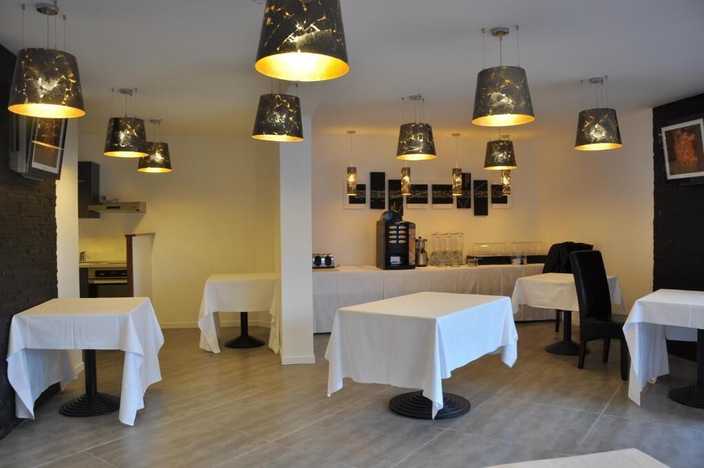 Interior de restaurante con varias mesas y lámparas colgantes.