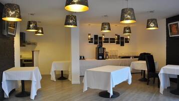 Interior de restaurante con varias mesas y lámparas colgantes.