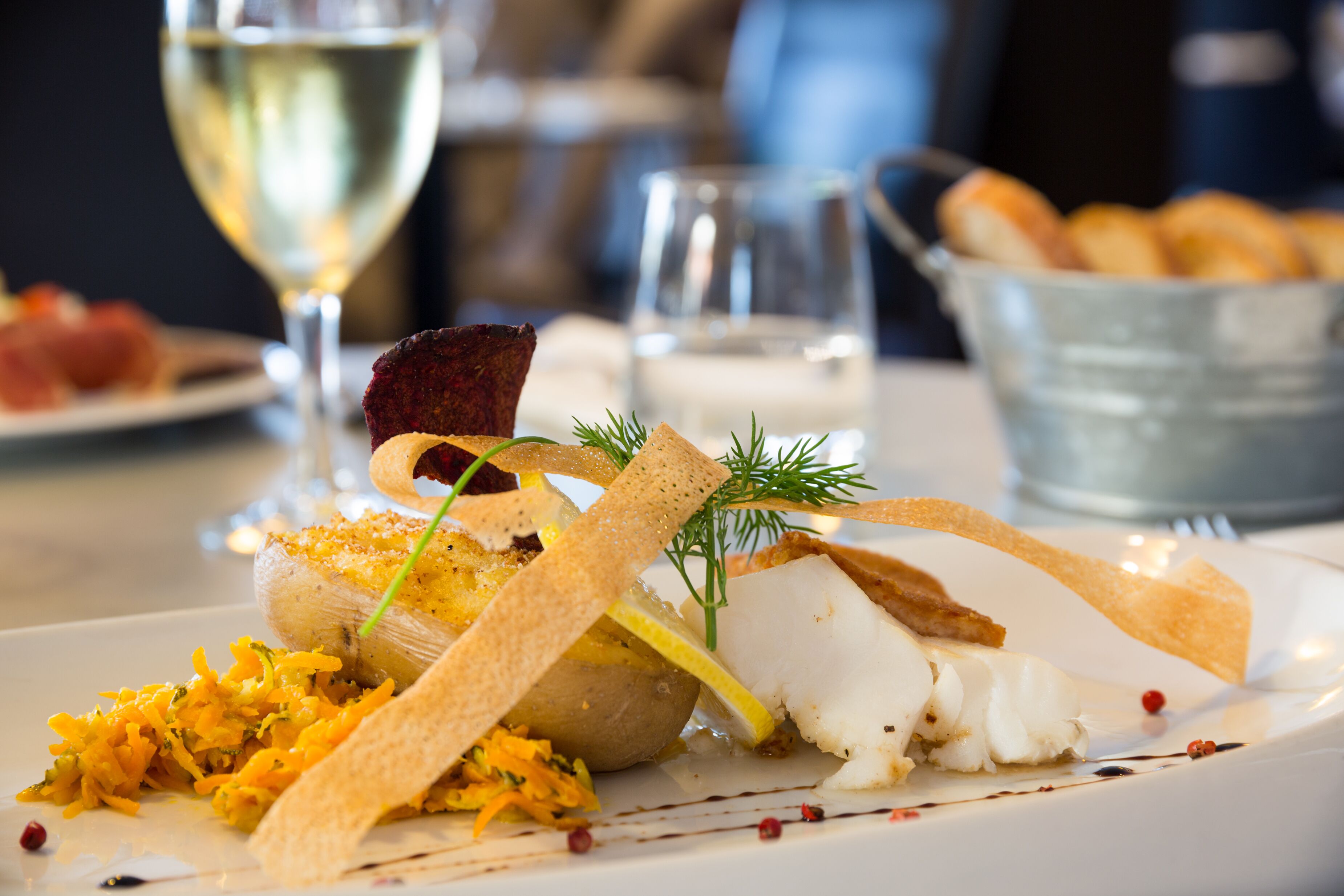 A plate of food with various items including fish, vegetables, and garnishes.