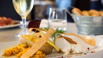 A plate of food with various items including fish, vegetables, and garnishes.