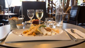 A dining table with a white plate of food, wine glasses, a bottle, and cutlery. - The Originals City, Hôtel des Arts (Negrepelisse)